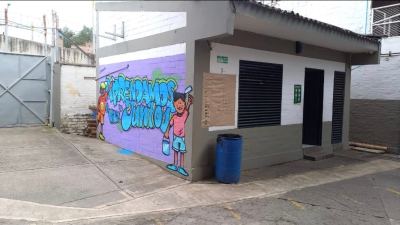 Entrada principal de la sede Juan Pablo II, junto a la coordinación, con un mensaje que promueve el aprendizaje colectivo.